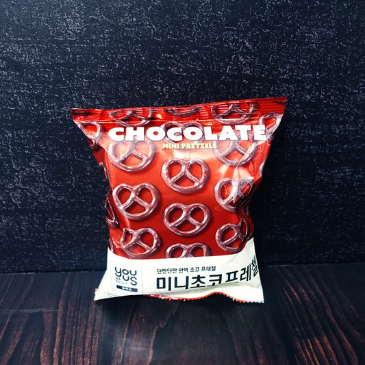 Red bag of You Us Chocolate Mini Pretzels with Korean text, on a dark wooden surface